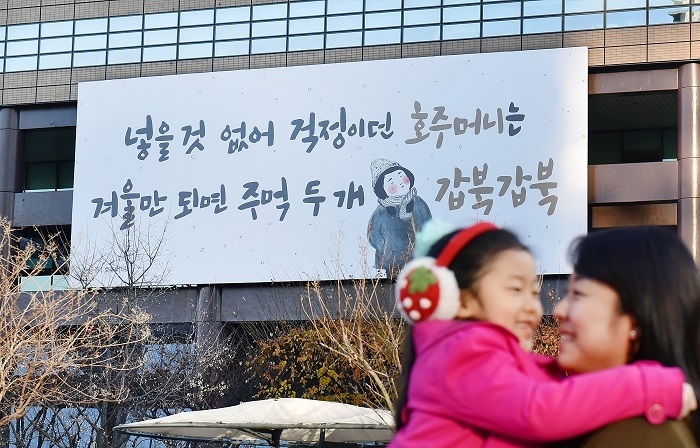 2일 교보생명 광화문글판 '겨울편'이 내걸린 광화문 교보생명빌딩 주변을 엄마와 아이가 걷고 있다. 이번 문안은 민족시인 윤동주의 동시 '호주머니'에서 가져왔다. 입을 것, 먹을 것 모두 모자랐던 일제강점기에 쓰여진 시로, 힘든 현실이지만 호주머니 속 두 주먹을 불끈 쥐며 힘을 내라는 위로를 건넨다. (사진=교보생명)