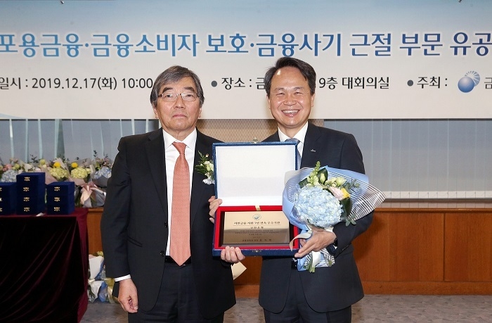 17일 서울 여의도 소재 금융감독원에서 열린 ‘2019 포용금융·금융소비자보호·금융사기근절 부문 등 유공자 시상식’에서 ‘서민금융 지원 7년 연속 우수기관’으로 선정 후 금융감독원 윤석헌 원장(왼쪽)과 신한은행 진옥동 은행장(오른쪽)이 기념촬영 하는 모습. (사진=신한은행)