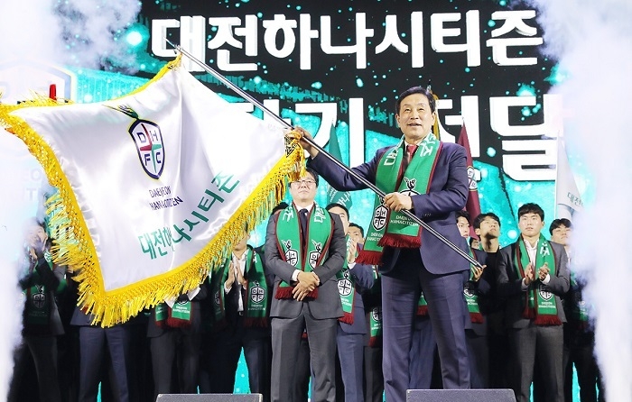 하나금융그룹(회장 김정태)은 지난 4일 대전 충무실내체육관에서 대전 시민들과 함께 새롭게 태어날 프로축구단 '대전하나시티즌'의 힘찬 도약을 알리는 창단식을 개최했다. 이 날 창단식에서 '대전하나시티즌'의 구단주인 김정태 하나금융 회장(사진 가운데)이 구단기를 힘차게 흔들고 있다. (사진=하나금융그룹)