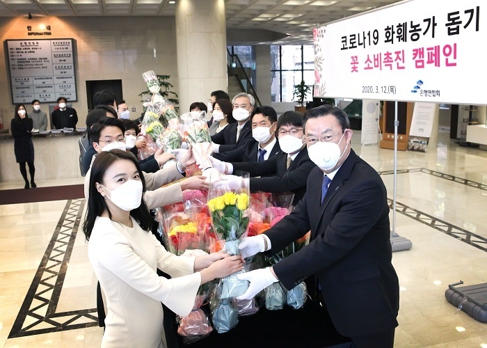 김태영 은행연합회 회장(오른쪽 맨 앞)을 비롯한 은행연합회 임원진들이 ‘꽃 소비 촉진 캠페인’에 동참하고자 12일 출근 중인 은행회관 입주사 임직원들에게 장미꽃을 나눠주고 있다. (사진=은행연합회)