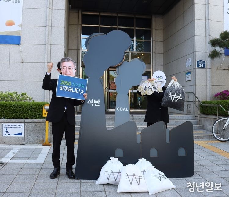 환경운동연합이 14일 국민연금공단 서울북부지역본부 정문 앞에서 국민연금공단의 석탄발전 사업 투자 중단을 촉구하며 퍼포먼스를 진행하고 있다. ‘2050 탄소중립’을 선언하는 문재인 대통령의 탈을 사람과 그 앞 대형 석탄발전소에 국민연금 탈을 쓴 사람이 돈뭉치를 쌓아 올리는 모습