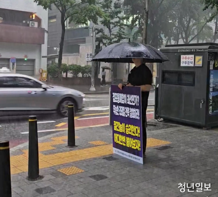지난 17일 SK증권 노조원이 폭우가 쏟아지는 속에 사옥 앞에서 점포 통폐합을 규탄하며 피켓 시위를 벌이고 있다. 