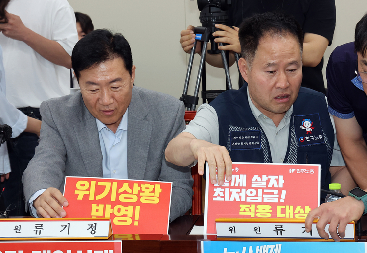 (왼쪽부터) 최저임금위원회 사용자위원인 류기정 한국경영자총협회 전무(와 근로자위원인 정문주 한국노총 중앙연구원장이 지난 10일 정부세종청사에서 열린 최저임금위원회 제4차 전원회의에서 자리 앞에 서로가 주장하는 의미가 담긴 손팻말을 놓고 있다. 