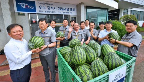 경기도 안산시 남양넥스모㈜ 대표와 직원들이 현대모비스가 전달한 수박을 들어보이며 활짝 웃고 있다. 현대모비스는 이달 말까지 AS순정 부품의 공급에 힘쓴 우수 협력사 250개사와 전국 1,300여 곳 대리점에 감사장과 함께 수박 1만여 통을 전달한다. [사진=현대모비스]